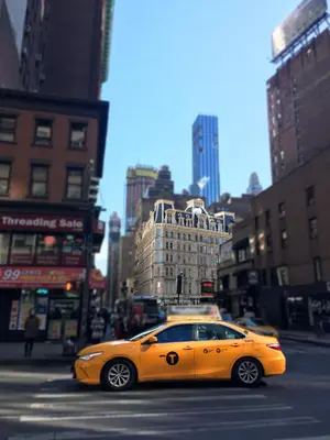 a yellow car is driving down a city street at NYC Empire Apartments in New York