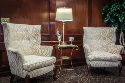 two chairs and a lamp in a room with wooden walls at The Olde Mill Inn Basking Ridge in Basking Ridge