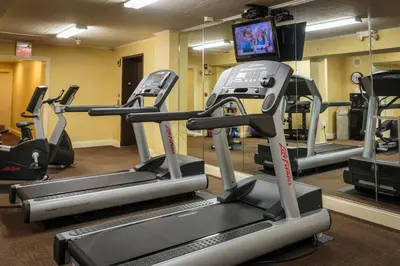 a gym with several tread machines and a flat screen tv at The Olde Mill Inn Basking Ridge in Basking Ridge