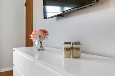 a white counter with two jars and a vase with flowers at Close to NYC | King Bed | Free Parking in Bloomfield