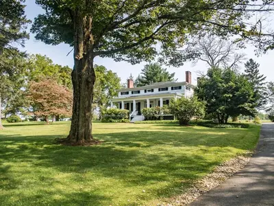 a large white house with a tree in the yard at The Neighbour House B&B in Long Valley