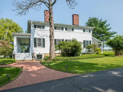 a white house with a tree and a brick driveway at The Neighbour House B&B in Long Valley