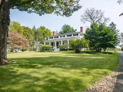 a large white house on a green lawn at The Neighbour House B&B in Long Valley