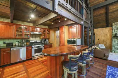 a kitchen with wooden cabinets and a bar with stools at ⛰⛵️⛱Mt. Maplewood Lodge❤️Seasonal Specials ☆Poconos☆Cabin☆Hot⛷Tub☆Game Room☆ in Pocono Pines