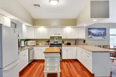 a kitchen with white cabinets and wooden floors at Mt. Maplewood Chalet in Pocono Lake