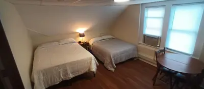 a bedroom with two beds and a table and window at Cappuccio Hotel in Keansburg