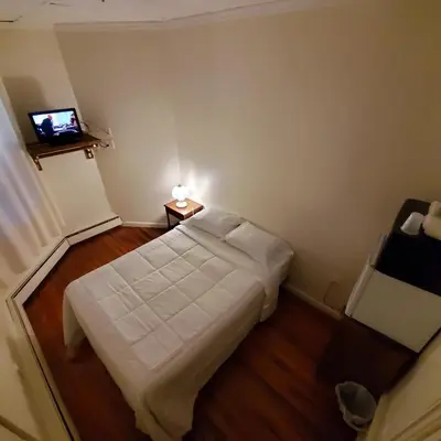 a small bedroom with a bed and a television at Cappuccio Hotel in Keansburg