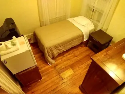 a small bedroom with a bed and two tables at Cappuccio Hotel in Keansburg