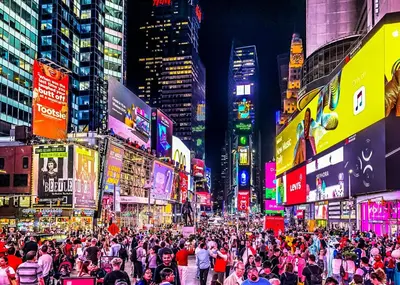 a crowd of people walking down a busy city street at night at TIME SQUARE 42nd Street Private Room in New York