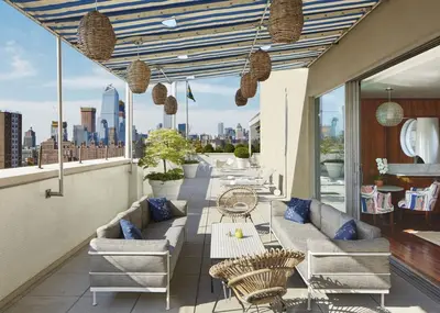 a balcony with couches and chairs and a view of the city at The Maritime Hotel in New York
