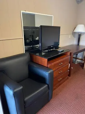 a room with a chair and a television on a dresser at Travel Inn in Horseheads