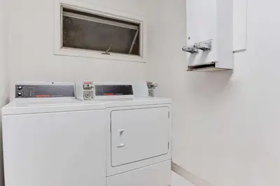 a white kitchen with a dishwasher and a window at Travel Inn in Horseheads