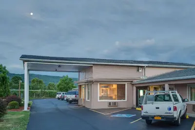 a building with a car parked in a parking lot at Travel Inn in Horseheads