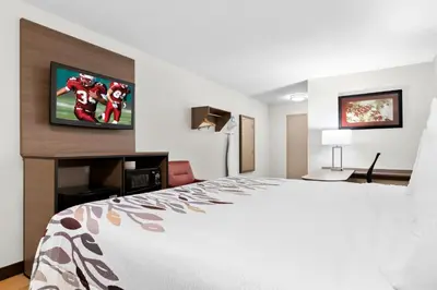 a hotel room with a bed and a flat screen tv at Red Roof Inn Harrisburg North in Harrisburg