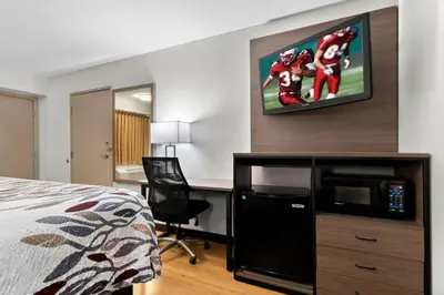 a hotel room with a bed and a desk with a tv at Red Roof Inn Harrisburg North in Harrisburg