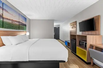 a hotel room with a bed and a flat screen tv at Days Inn by Wyndham Liberty in Ferndale