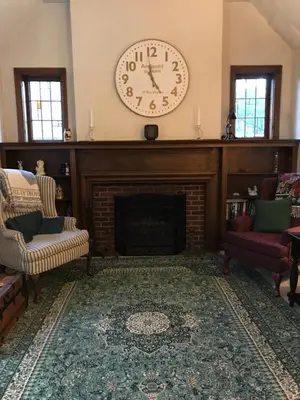 a living room with a fireplace with a clock on the wall at Mill Stone - Mt Penn Lodging in Mount Penn