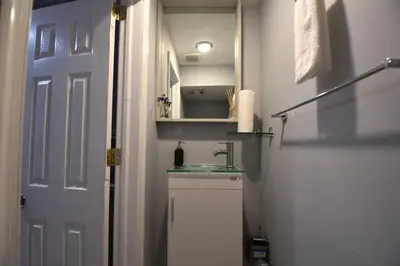 a small bathroom with a sink and a door at Tuscany 2900 - Classic Italian Style 3BR w Parking near Airport in Philadelphia