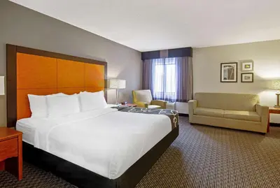 a hotel room with a large bed and a chair at La Quinta by Wyndham Harrisburg Airport Hershey in Harrisburg