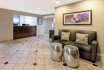 a waiting room with a couch and two metal stools at La Quinta by Wyndham Harrisburg Airport Hershey in Harrisburg