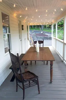 a wooden table and chairs on a porch at Stonehill's Farmhouse in Accord