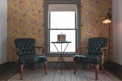 two chairs and a table in a room with wallpaper at Stonehill's Farmhouse in Accord
