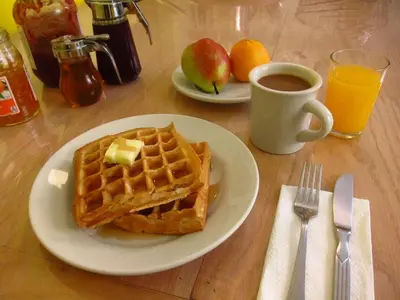 a table with a plate of waffles and a cup of coffee at American Dream in New York