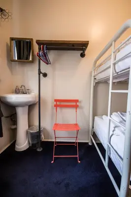 a red chair in a room with a sink and bunk beds at American Dream in New York