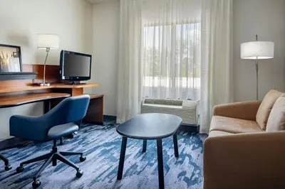 a hotel room with a couch and a desk and chair at Fairfield Inn & Suites by Marriott Towanda Wysox in Towanda