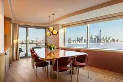 a dining room with a table and chairs and a large window at W Hoboken in Hoboken