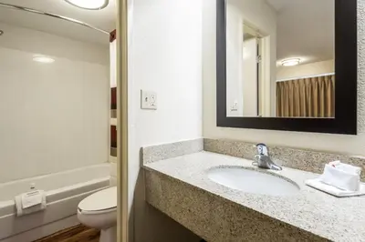 a bathroom with a sink and a toilet and a mirror at Red Roof Inn Edison in Edison