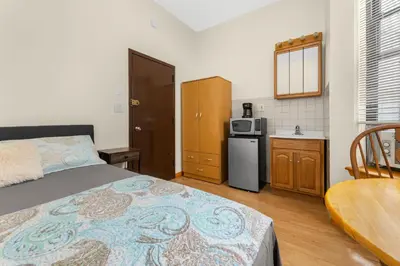 a bedroom with a bed and a kitchen with a microwave at West 30th Street Guest House in New York