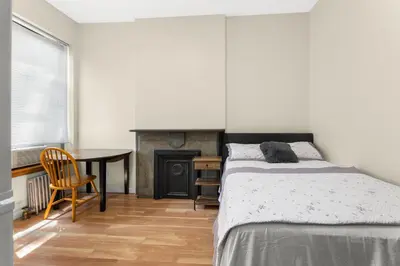 a bedroom with a bed and a desk and a fireplace at West 30th Street Guest House in New York