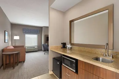 a hotel room with a sink and a living room at Hampton Inn & Suites Harrisburg in Harrisburg