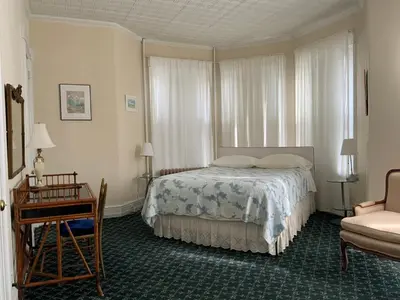 a bedroom with a bed and a table and a chair at Fort Pl B&B and Gallery in Staten Island