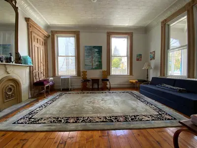 a living room with a blue couch and a rug at Fort Pl B&B and Gallery in Staten Island
