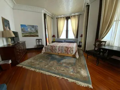 a bedroom with a bed and a table and a piano at Fort Pl B&B and Gallery in Staten Island