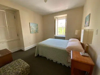 a bedroom with a bed and a table and a window at Fort Pl B&B and Gallery in Staten Island