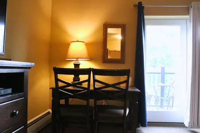 a lamp and a chair in a room with a window at The Lodge at Woodstone Country Club in Danielsville
