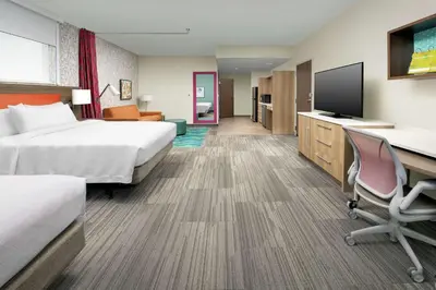 a hotel room with two beds and a desk and a tv at Home2 Suites By Hilton Edison in Edison
