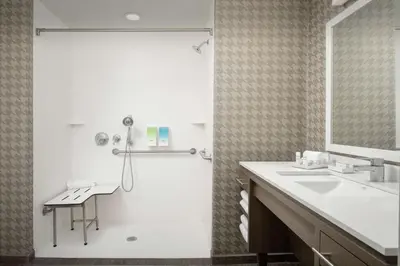 a bathroom with a shower and a sink and a mirror at Home2 Suites By Hilton Edison in Edison