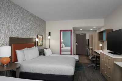 a hotel room with two beds and a desk at Home2 Suites By Hilton Edison in Edison