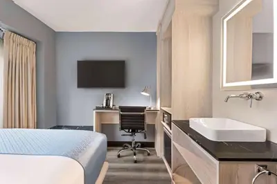 a hotel room with a bed and a desk and a sink at Wingate by Wyndham New York Midtown South/5th Ave in New York