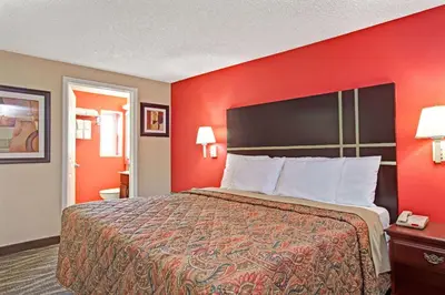 a hotel room with a bed and a red wall at Days Inn by Wyndham Ridgefield NJ in Ridgefield