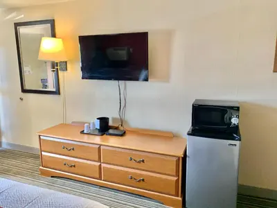 a hotel room with a television and a dresser with a microwave at Scottish Inns and Suites- Bordentown, NJ in Bordentown