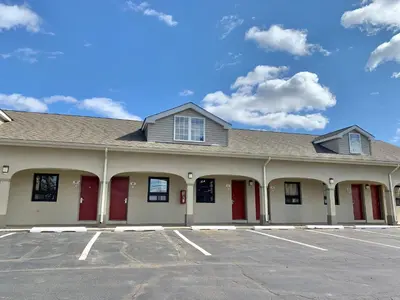 a building with red doors in a parking lot at Scottish Inns and Suites- Bordentown, NJ in Bordentown