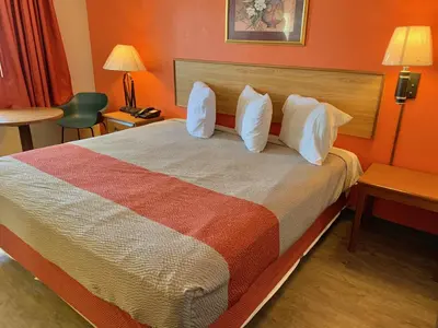 a hotel room with a large bed with white pillows at Scottish Inns and Suites- Bordentown, NJ in Bordentown