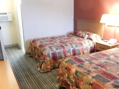 a hotel room with two beds and a lamp at Scottish Inns and Suites- Bordentown, NJ in Bordentown