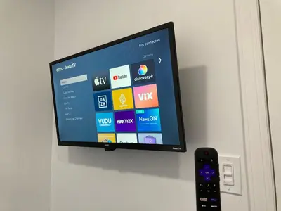 a flat screen tv hanging on a wall with a remote control at Modern GuestHouse Ironbound Newark with KITCHEN-FastTrainToNYC-OneStopToAirport in Newark