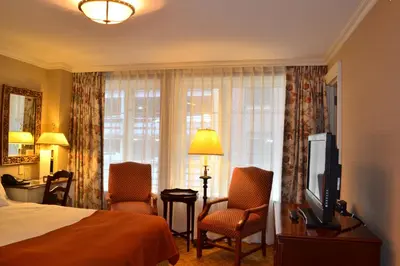 a hotel room with a bed and two chairs and a television at The Wall Street Inn in New York